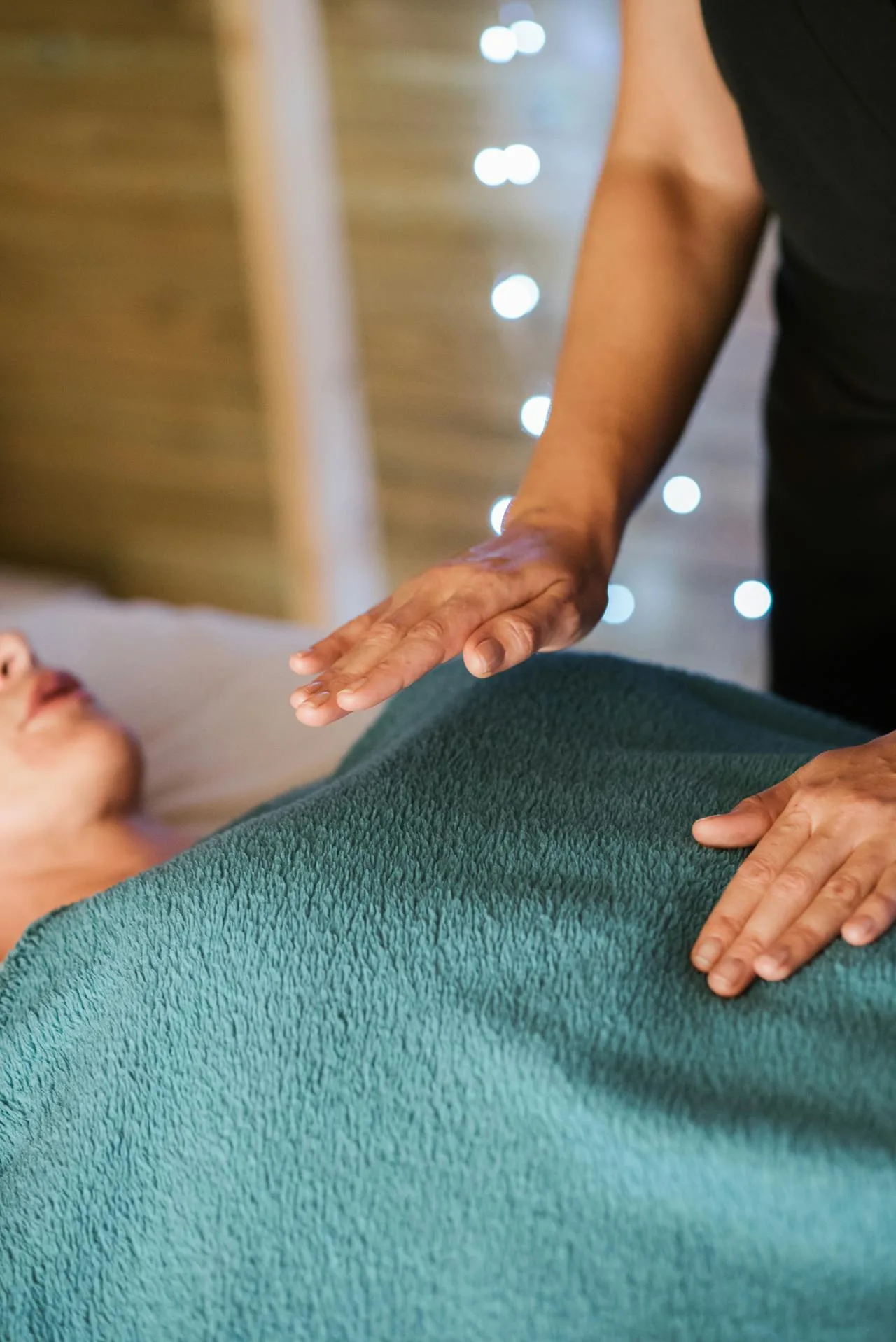 Praticienne posant les mains au-dessus d'une personne allongée sur table de soin